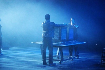 Andre and Tim on stage with prop, bathed in blue light, taken from the wings
